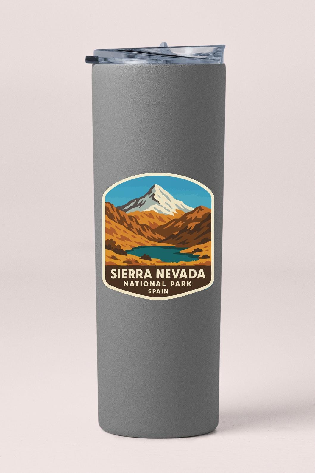 A gray insulated tumbler with a label that features an illustration of a mountain range and the text "Sierra Nevada National Park" and "Spanish" below it.