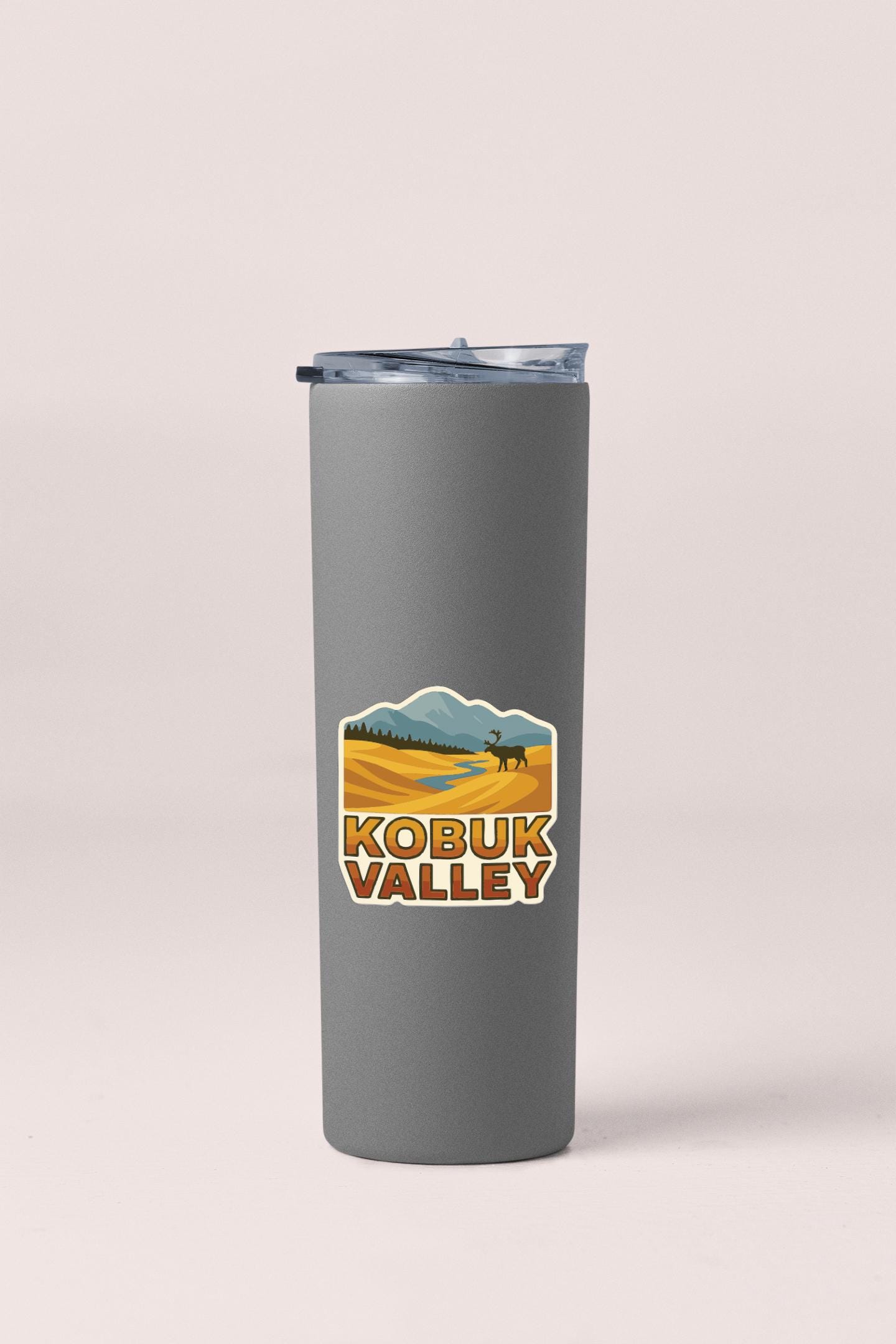 A gray insulated tumbler with a lid and a sticker depicting a scenic landscape with mountains and a river.