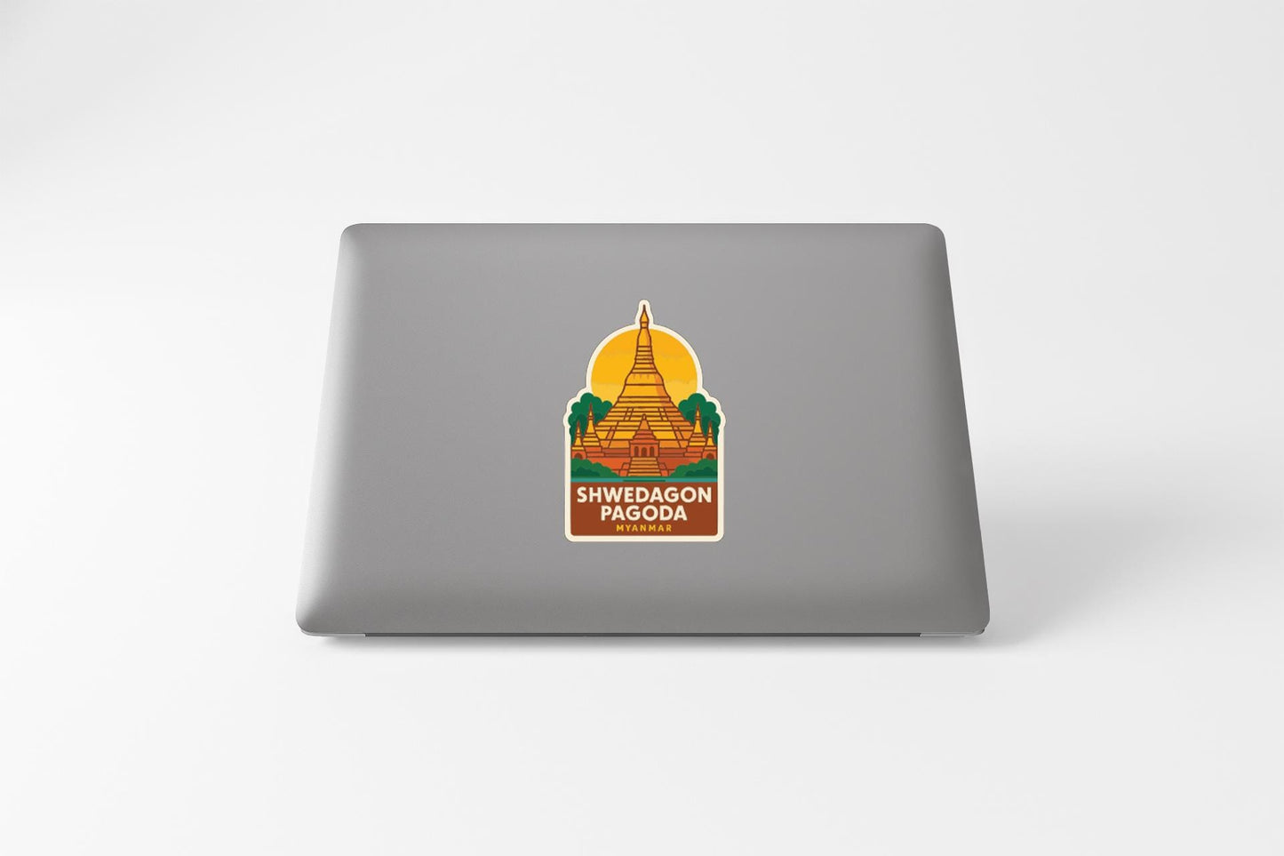 A sticker on the back of a laptop, depicting a temple with a yellow sun in the background.