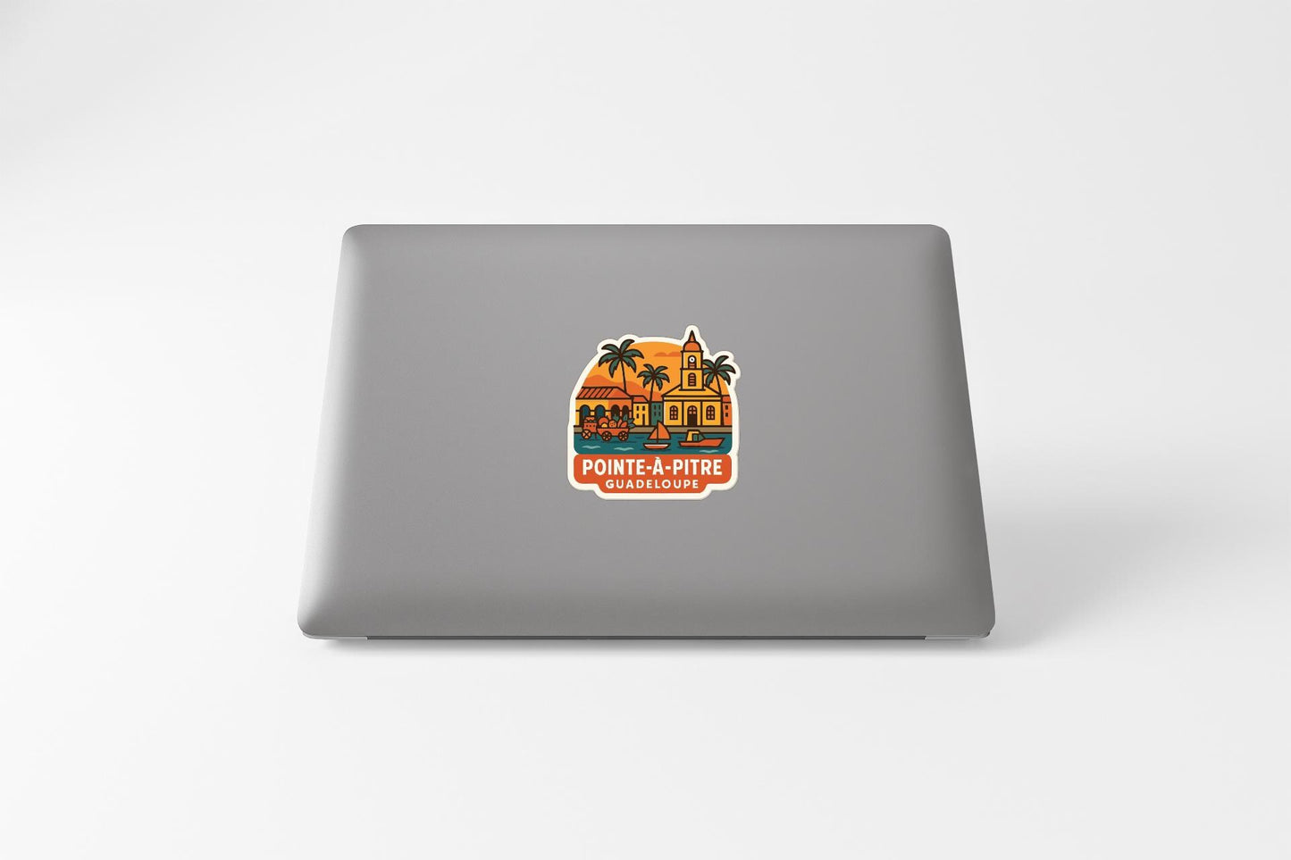 a sticker on the back of a laptop that depicts a tropical scene with palm trees and a building.