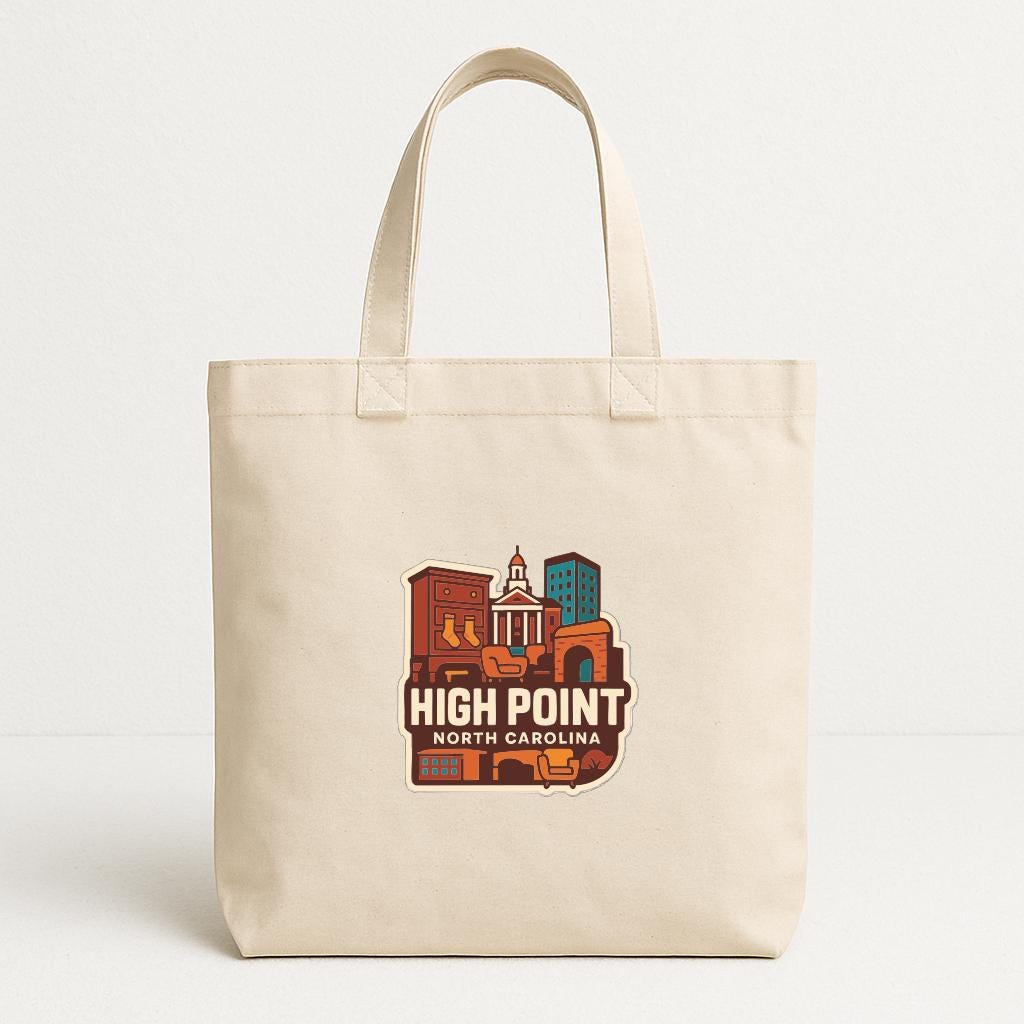 A beige tote bag with a printed design depicting a cityscape and the text "HIGH POINT NORTH CAROLINA".