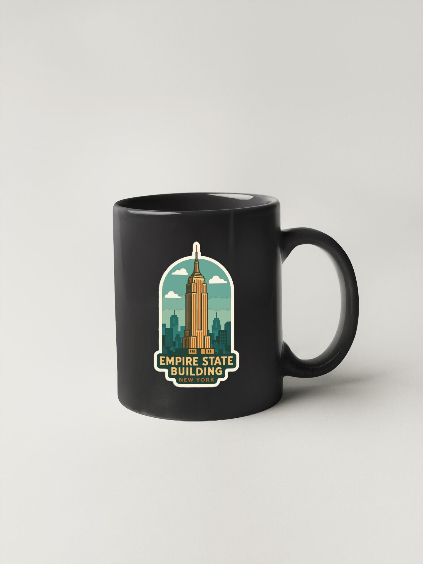 A black coffee mug with a graphic design featuring the Empire State Building and the text "Empire State Building NEW YORK".