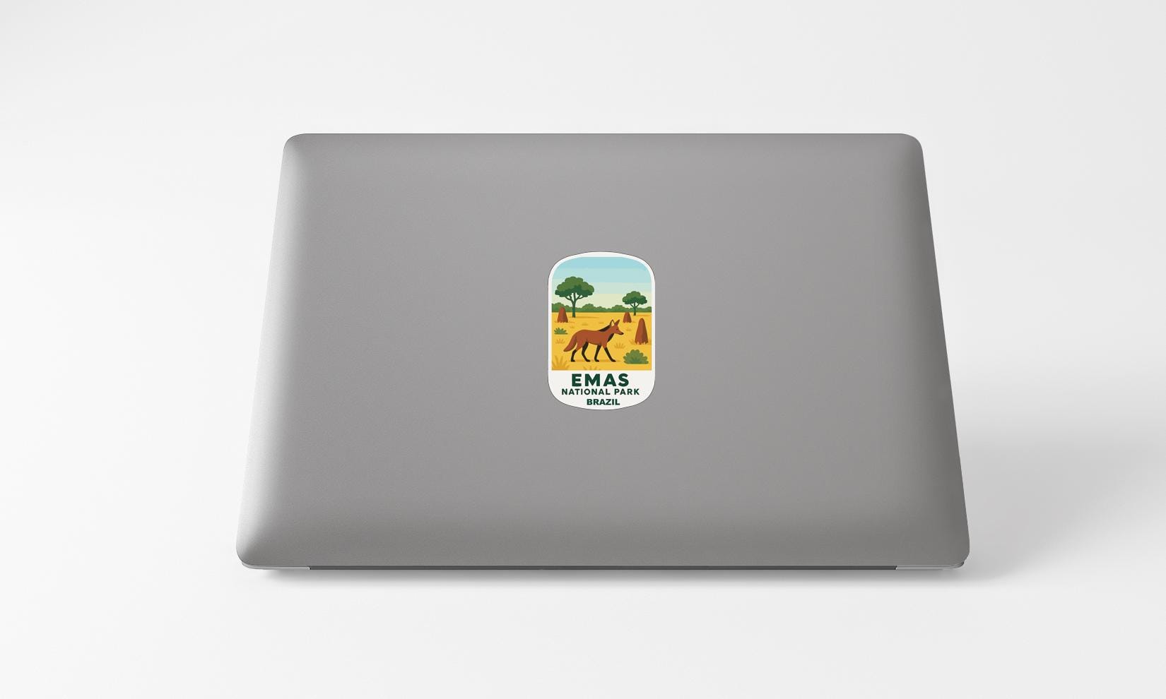 A sticker on the back of a laptop displaying an illustration of a dog in a field with trees in the background.