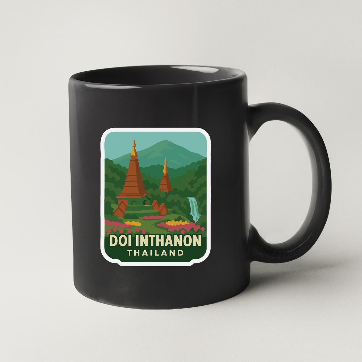 A black coffee mug with a sticker depicting the Doi Inthanon temple in Thailand.