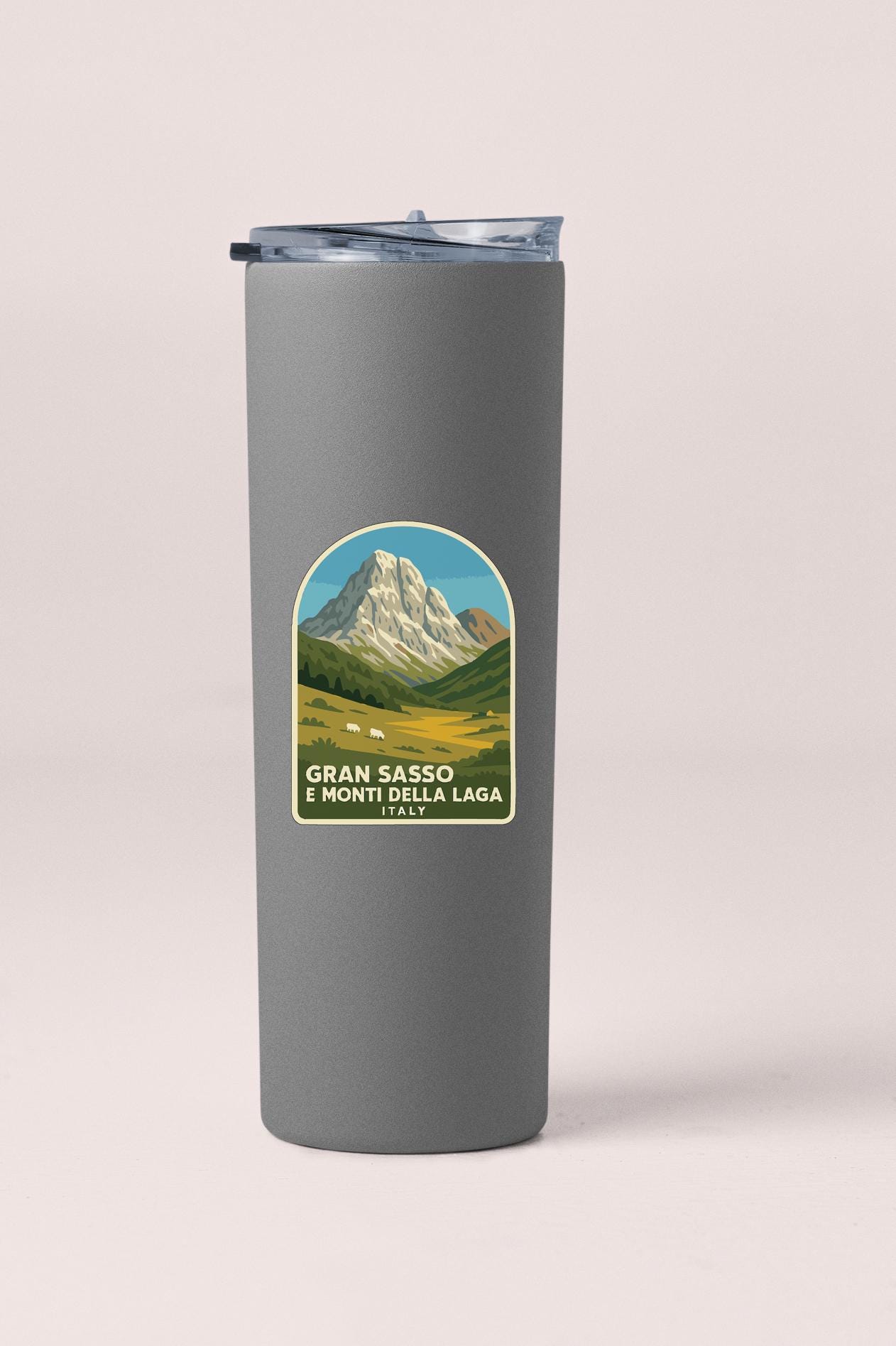 A gray insulated tumbler with a label featuring a mountain landscape and text.