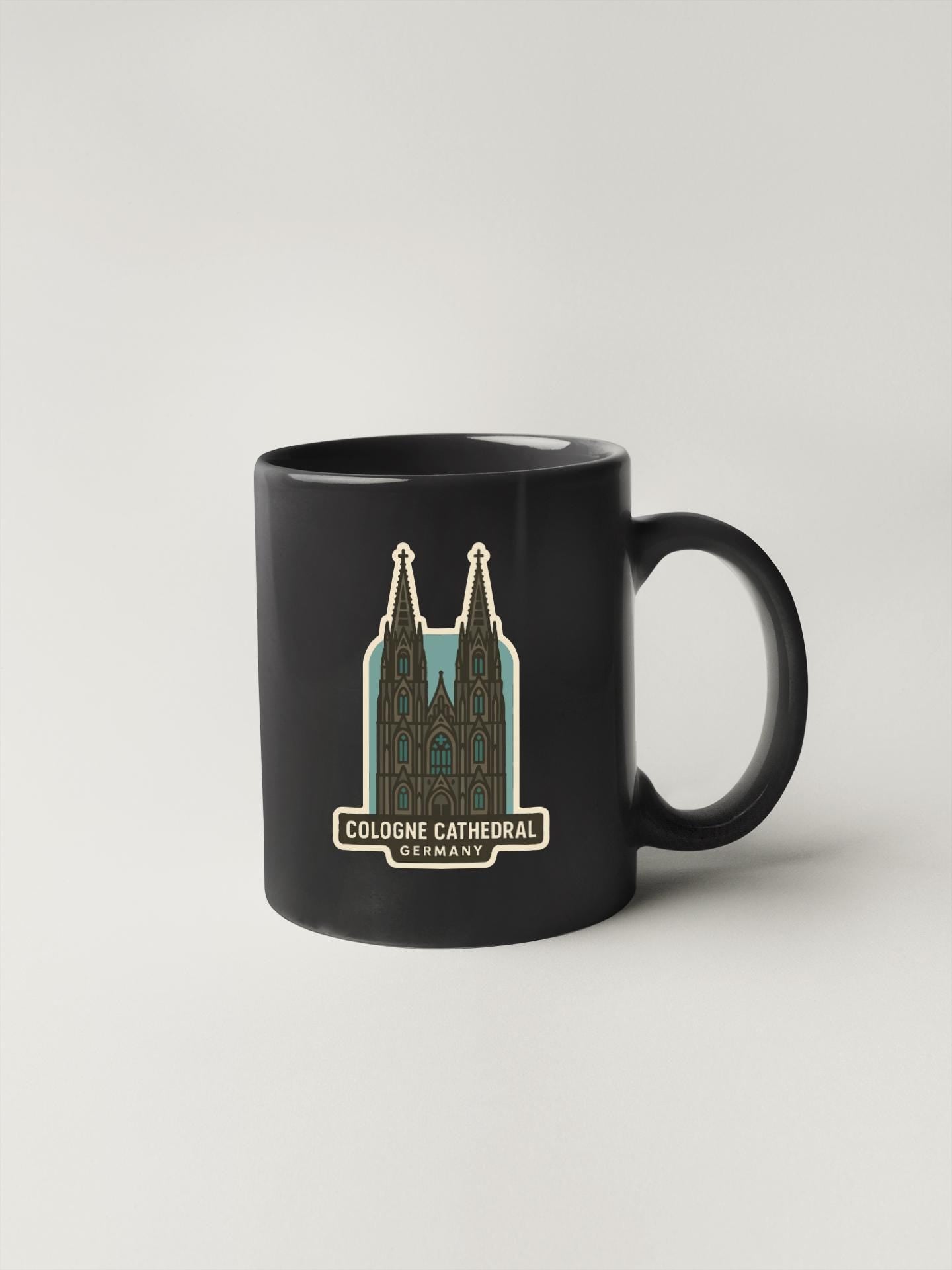 A black coffee mug with a graphic of the Cologne Cathedral in Germany printed on it.