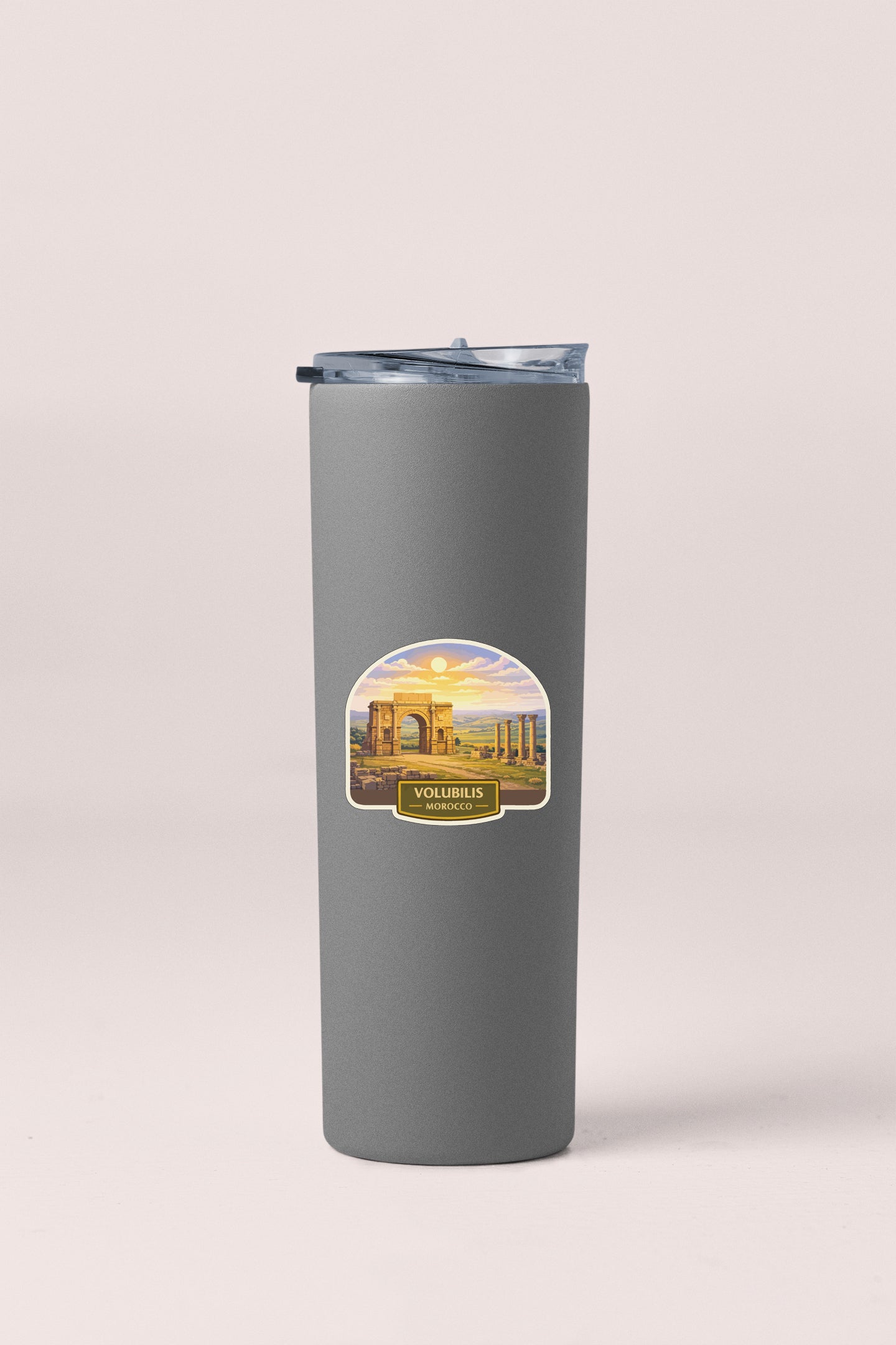 A gray insulated tumbler with a label depicting a scenic view of Volubilis, Morocco.