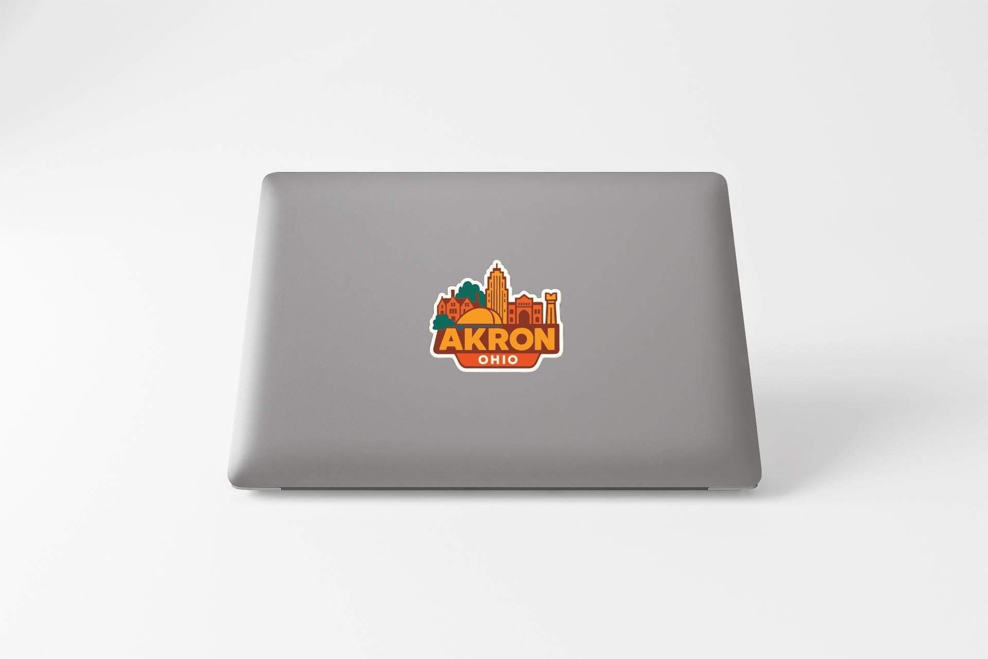 a sticker with a cityscape and the text "AKRON OHIO" on the back of a laptop.