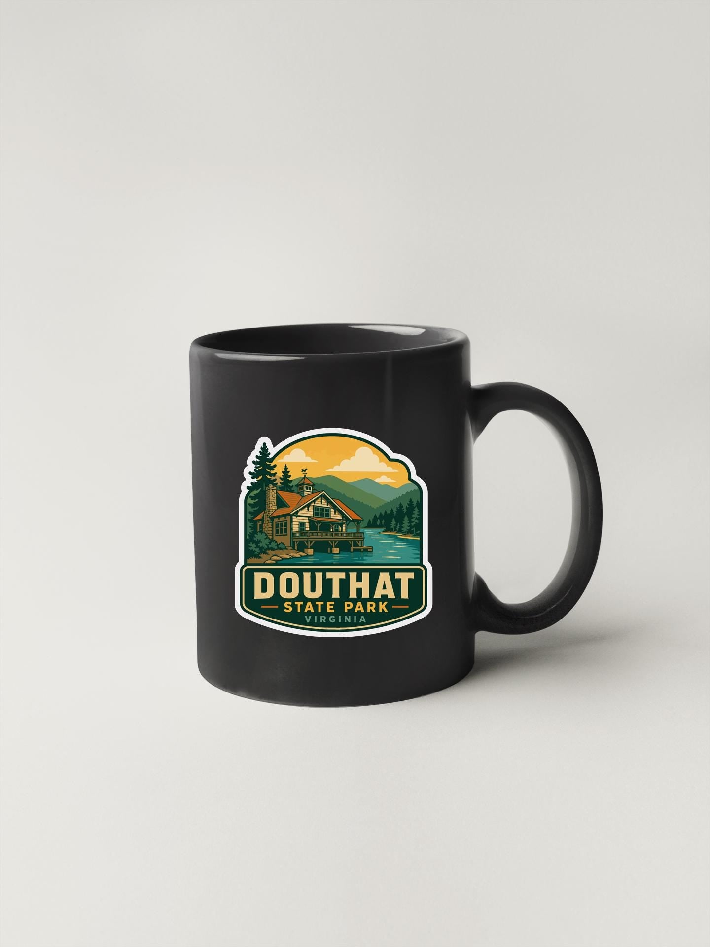 A black coffee mug with a graphic design depicting a cabin and a mountain landscape, along with the text "DOUTHAT STATE PARK" printed on it.