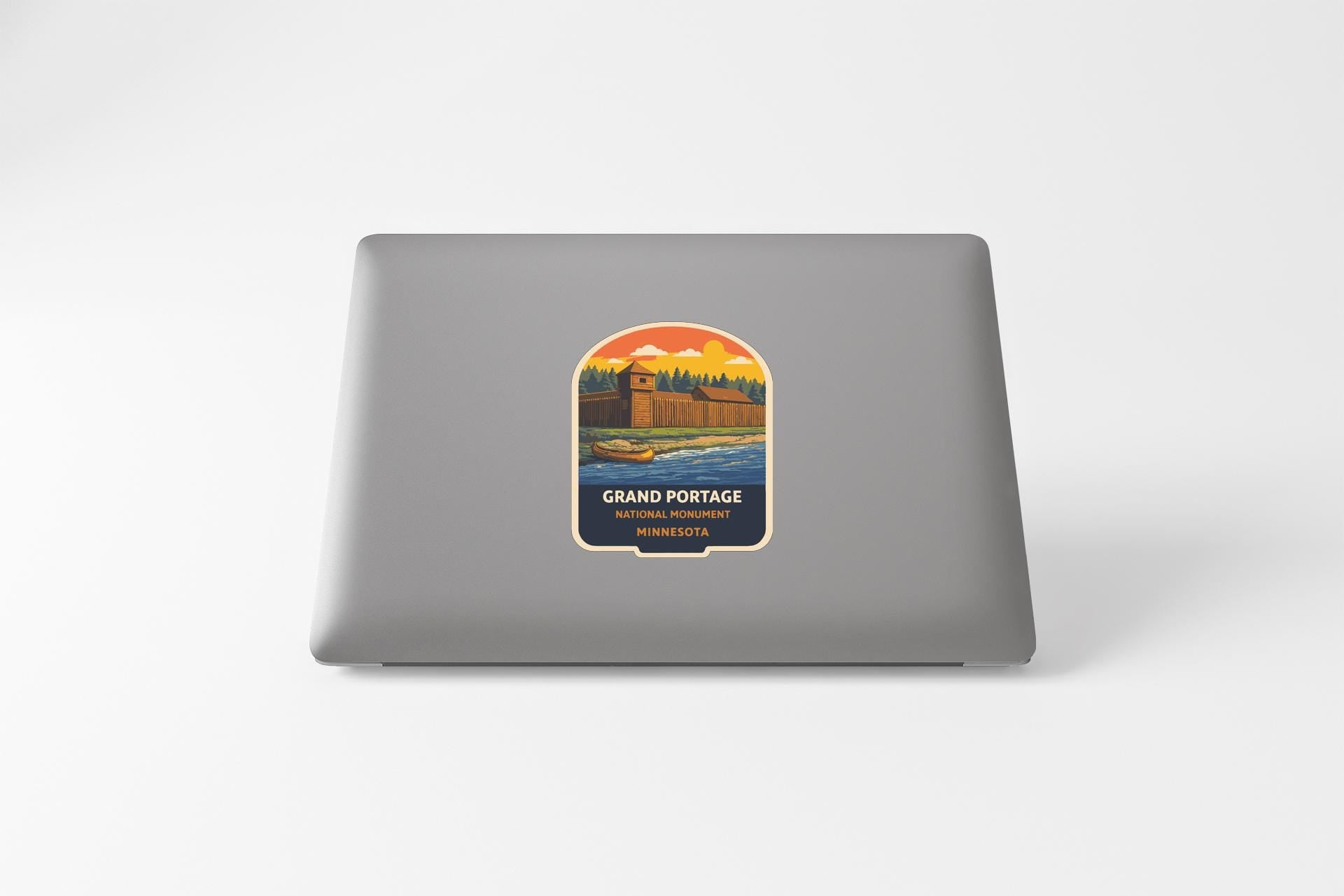 A sticker on the back of a laptop, depicting a scenic landscape with a castle or fortification in the background.