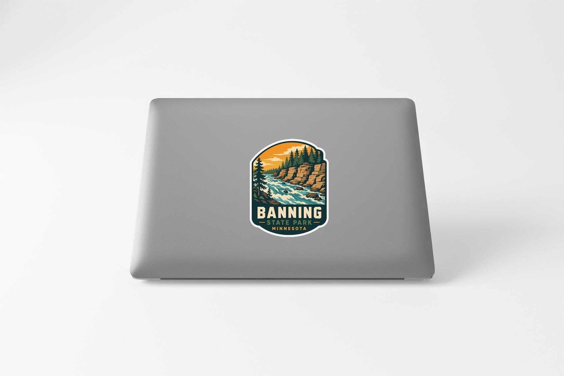 A sticker on the back of a laptop, depicting a scenic landscape with a river and mountains.