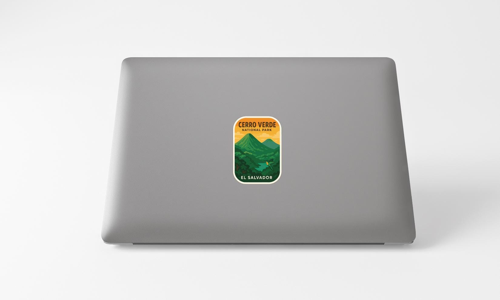A sticker on the back of a laptop, depicting a mountain landscape with a yellow and green color scheme.