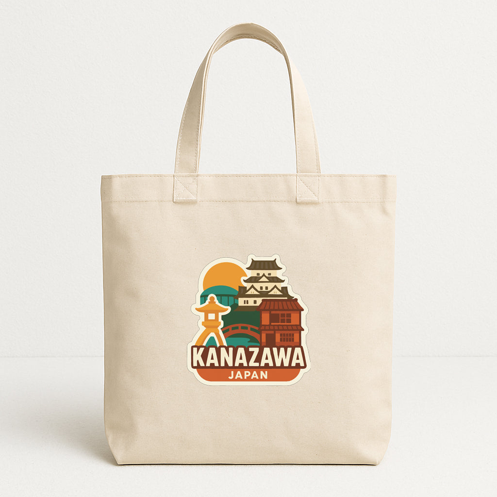 A beige tote bag with a printed design featuring a castle and a sun, along with the text "KANAZAWA JAPAN".