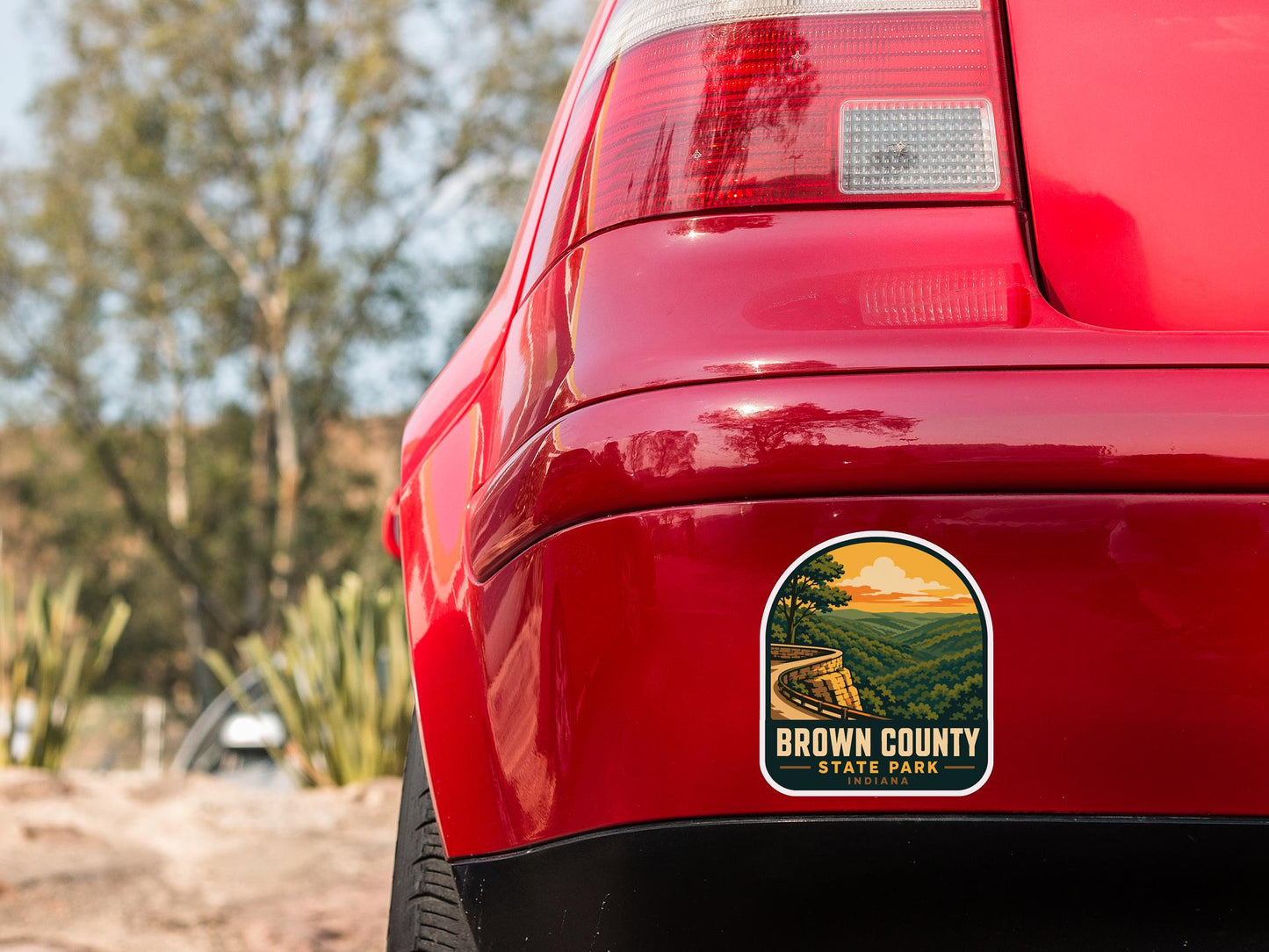 the rear end of a red car with a sticker on the back window that says "Brown County State Park".