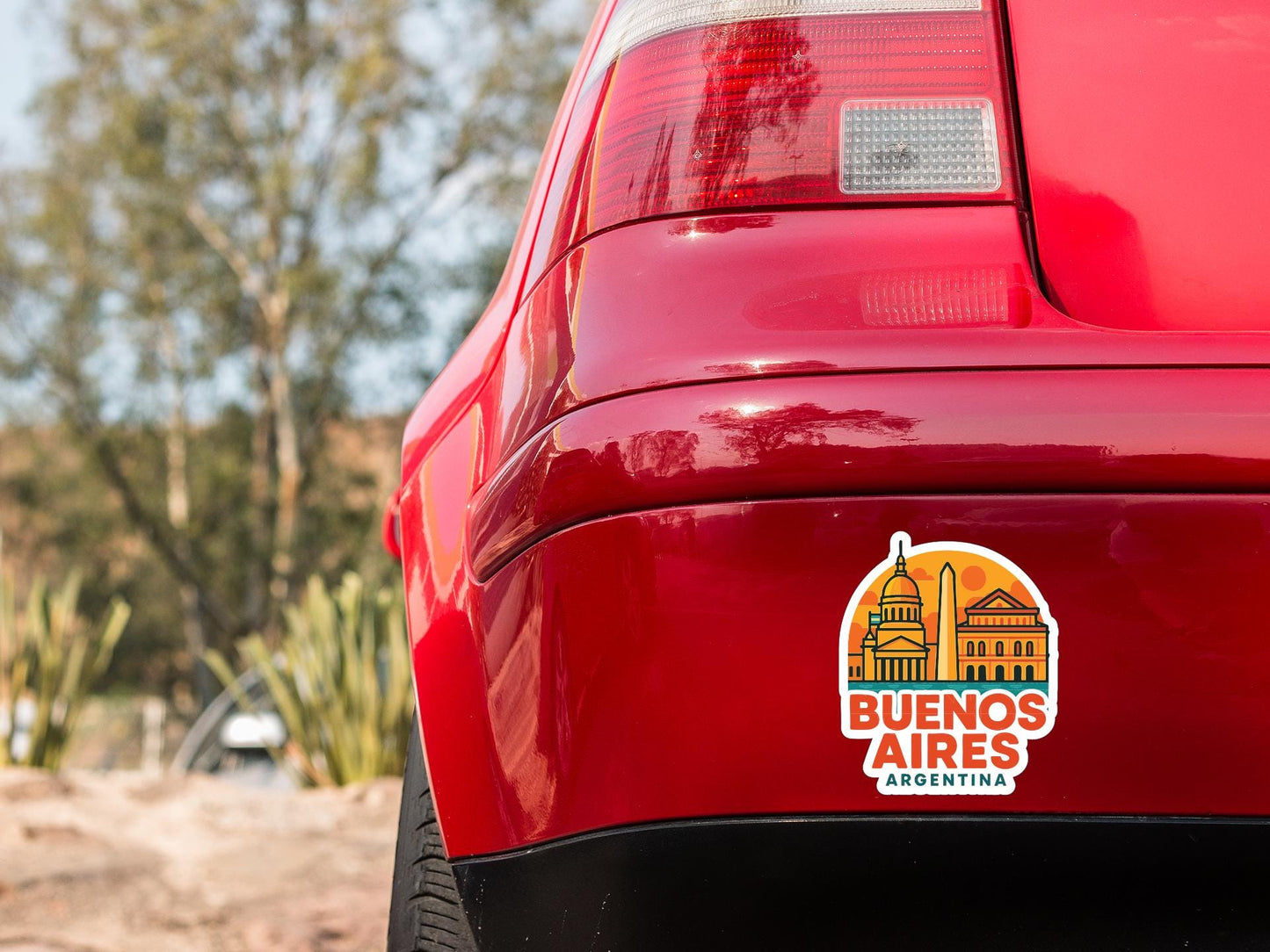 the rear end of a red car with a sticker on the trunk that says "Buenos Aires, Argentina".
