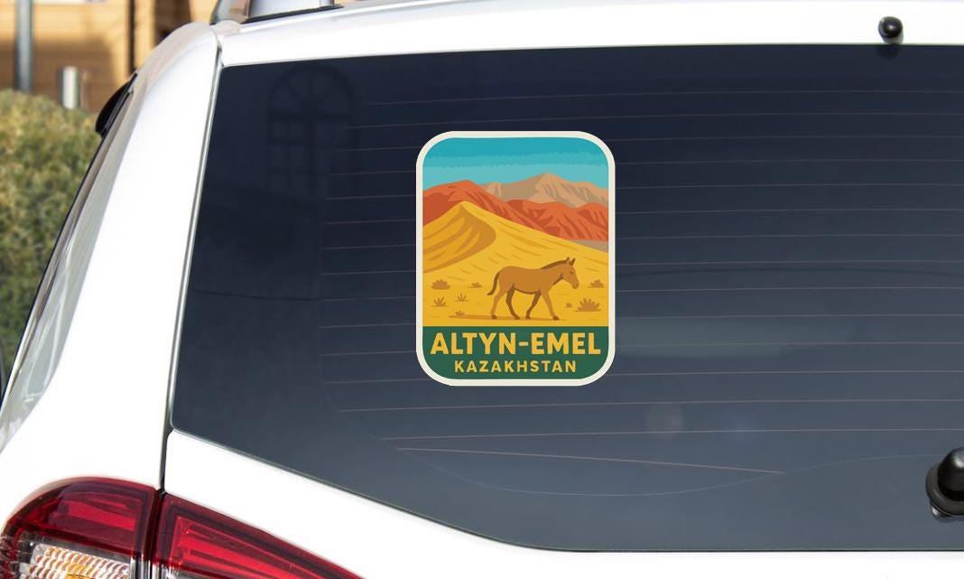 a sticker on the rear window of a vehicle, depicting a desert landscape with mountains in the background.