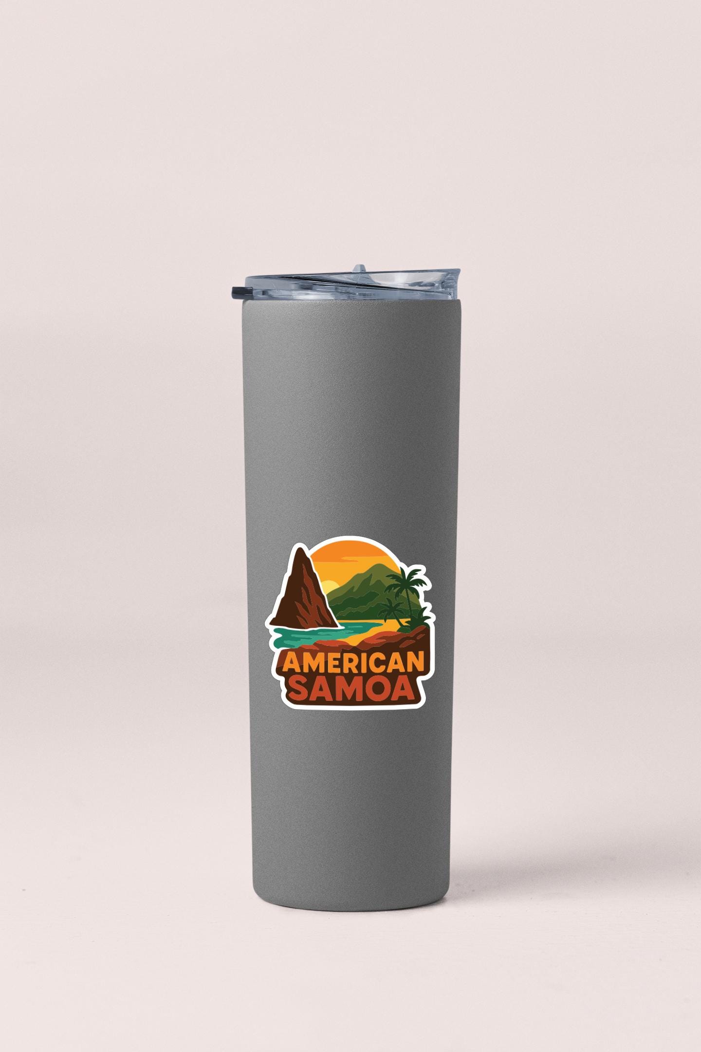 A gray insulated tumbler with a sticker depicting a tropical landscape, including mountains, palm trees, and a sunset.