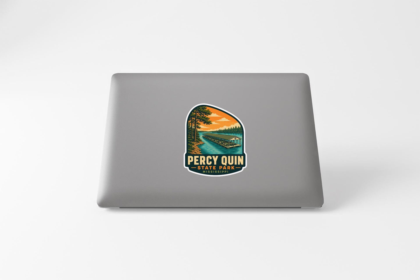 A sticker on the back of a laptop, depicting a scenic landscape with a lake, trees, and a boat.