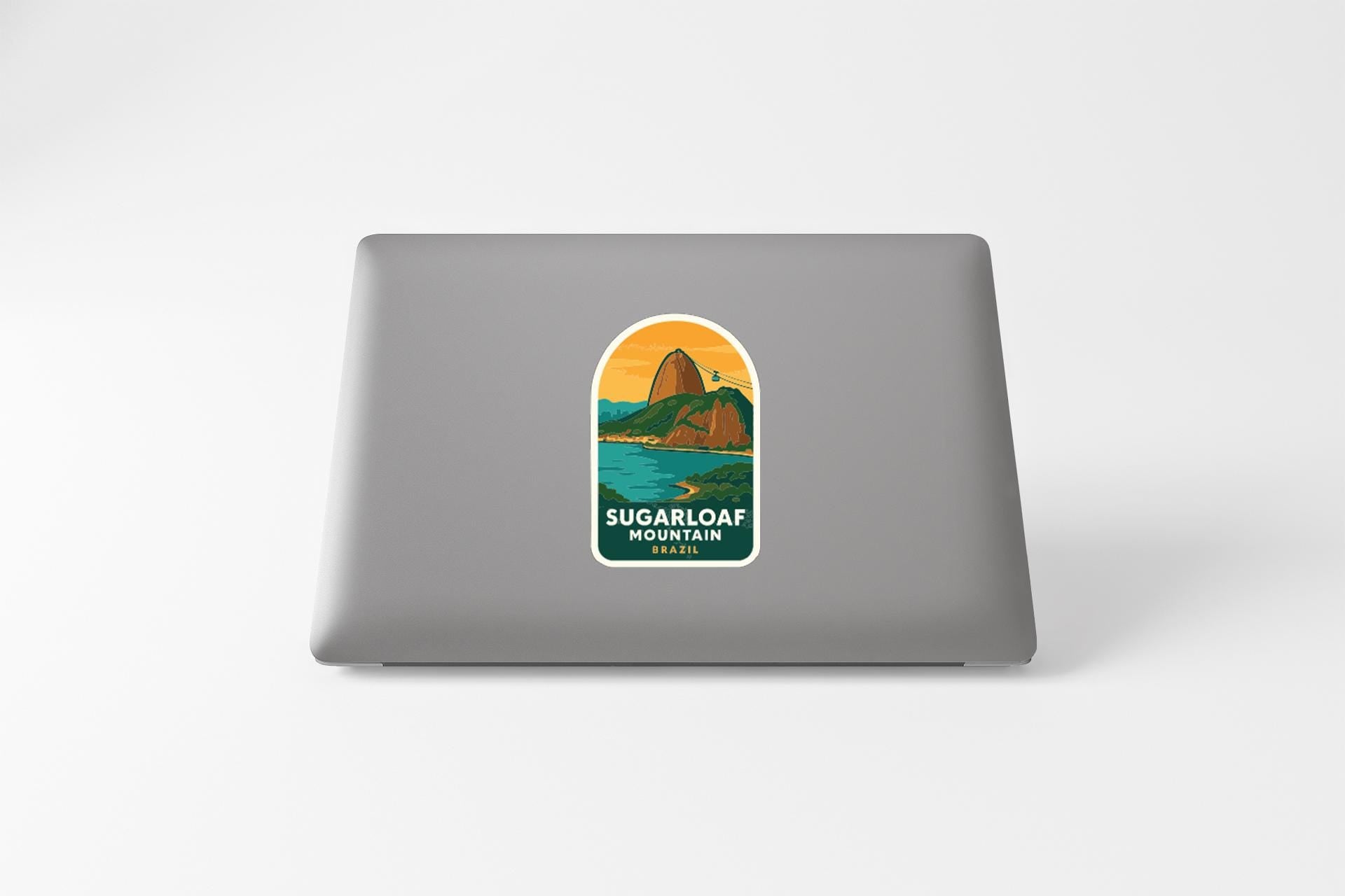 a sticker with a mountain landscape and water, placed on the back of a laptop.