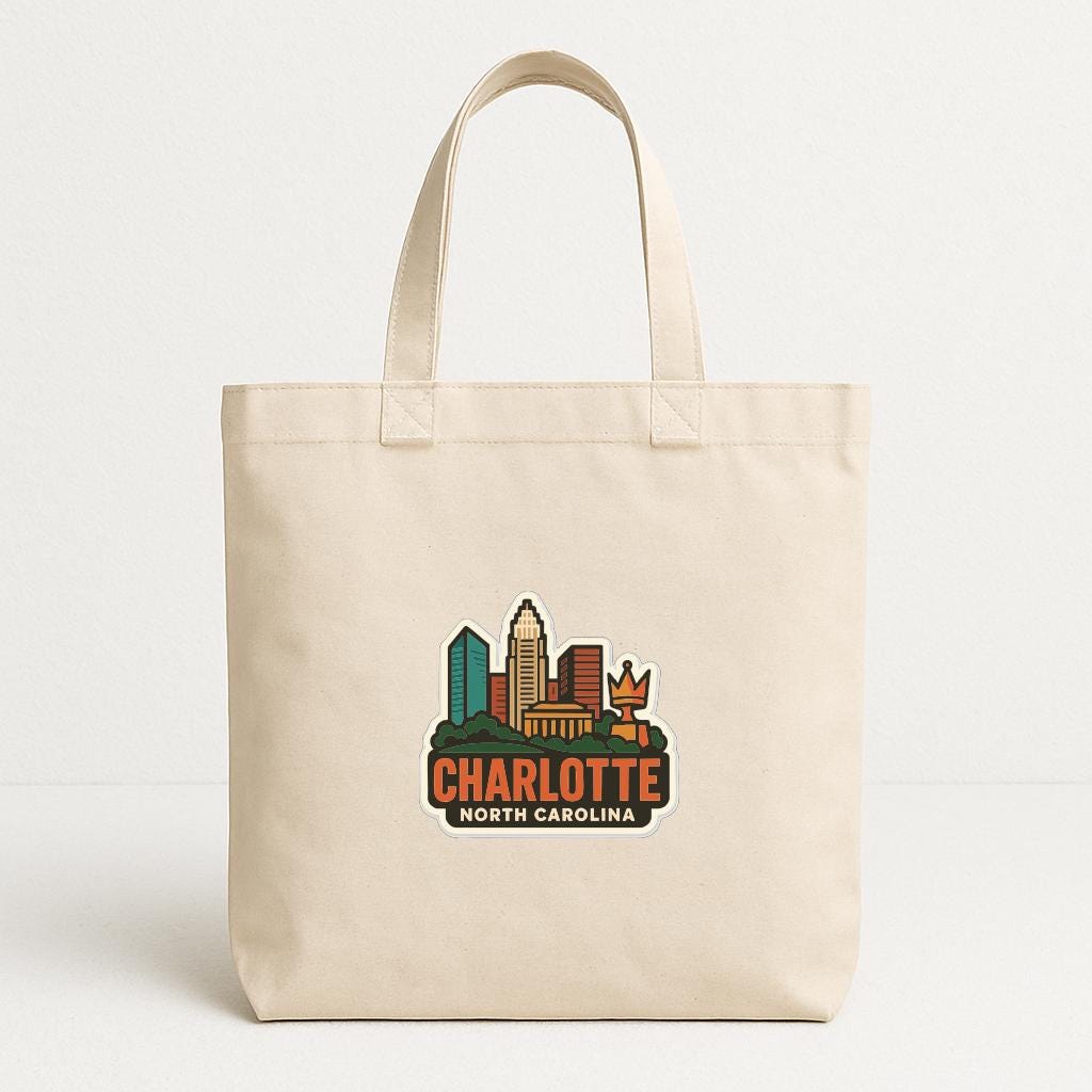 A beige tote bag with a printed design of the skyline of Charlotte, North Carolina.