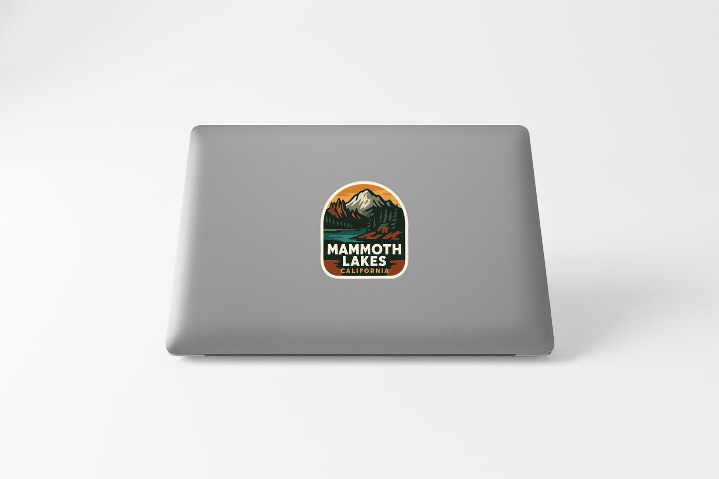 a sticker with a mountain and lake design on the back of a laptop.