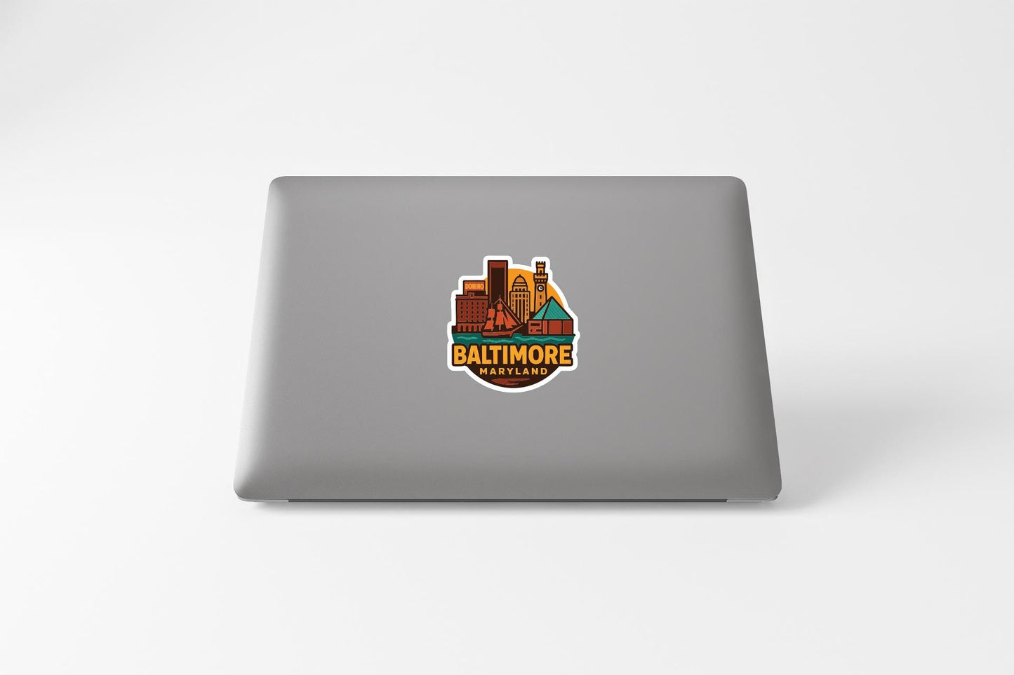 a sticker with a cityscape and the text "BALTIMORE" on a laptop.