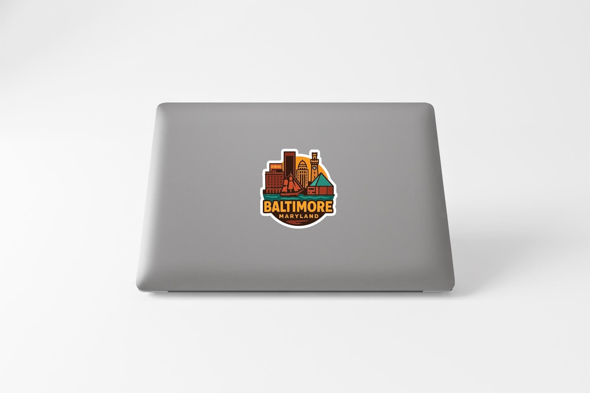 a sticker with a cityscape and the text "BALTIMORE" on a laptop.