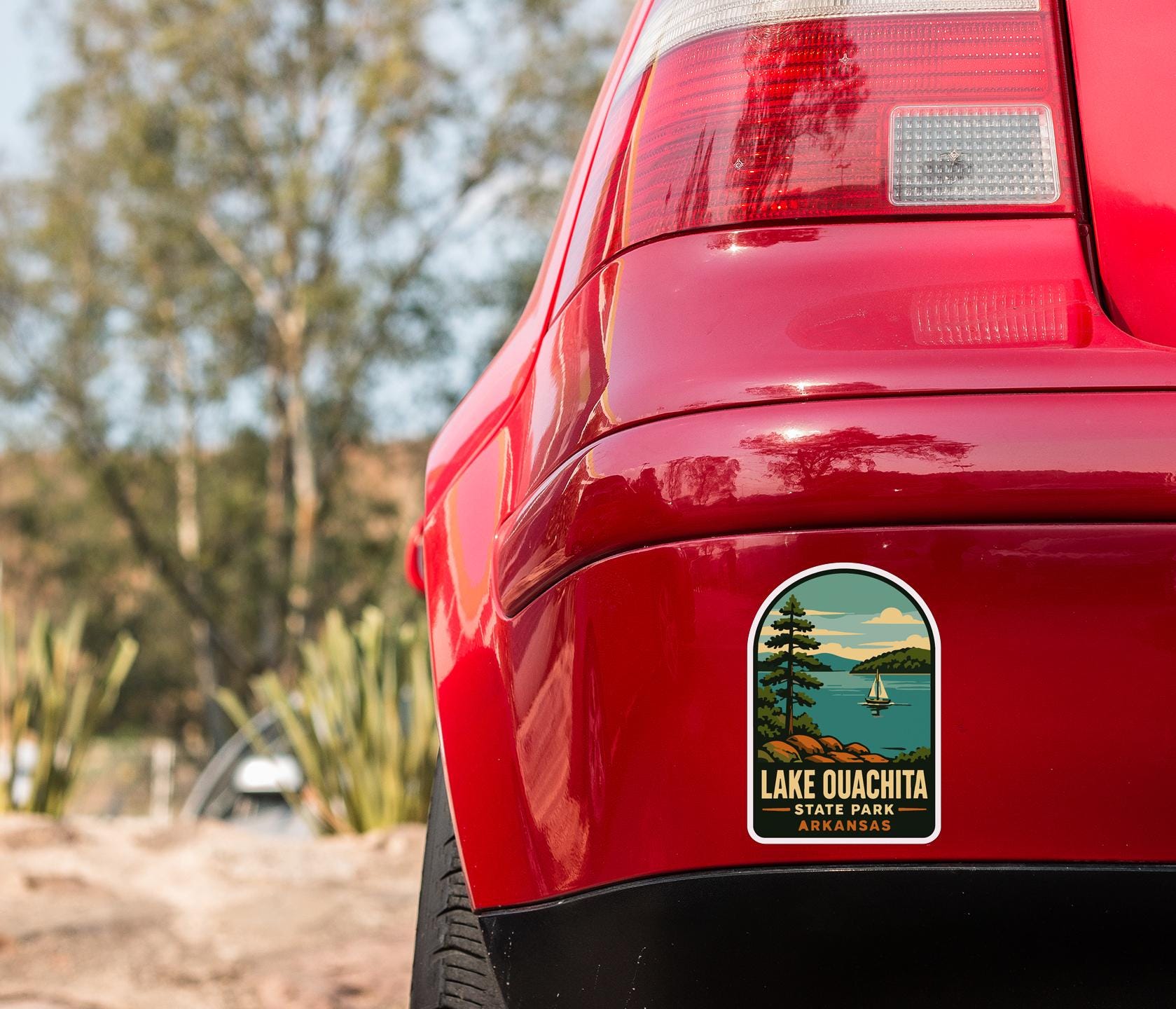 the rear end of a red car with a sticker on the trunk that says "Lake Quachita State Park Arkansas".
