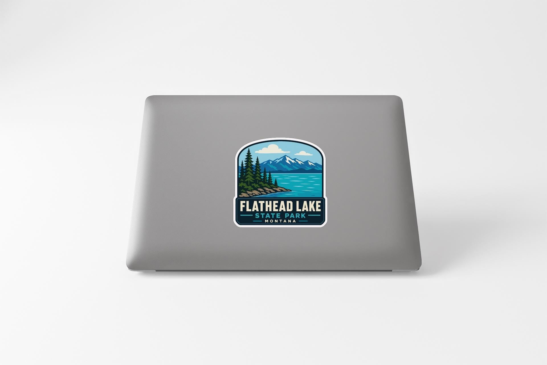 a sticker on a laptop that displays a scenic mountain landscape with a lake and pine trees.