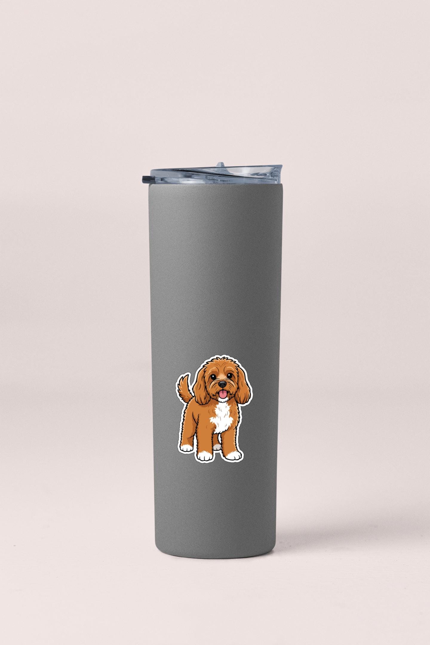A gray insulated tumbler with a sticker of a brown and white dog on it.