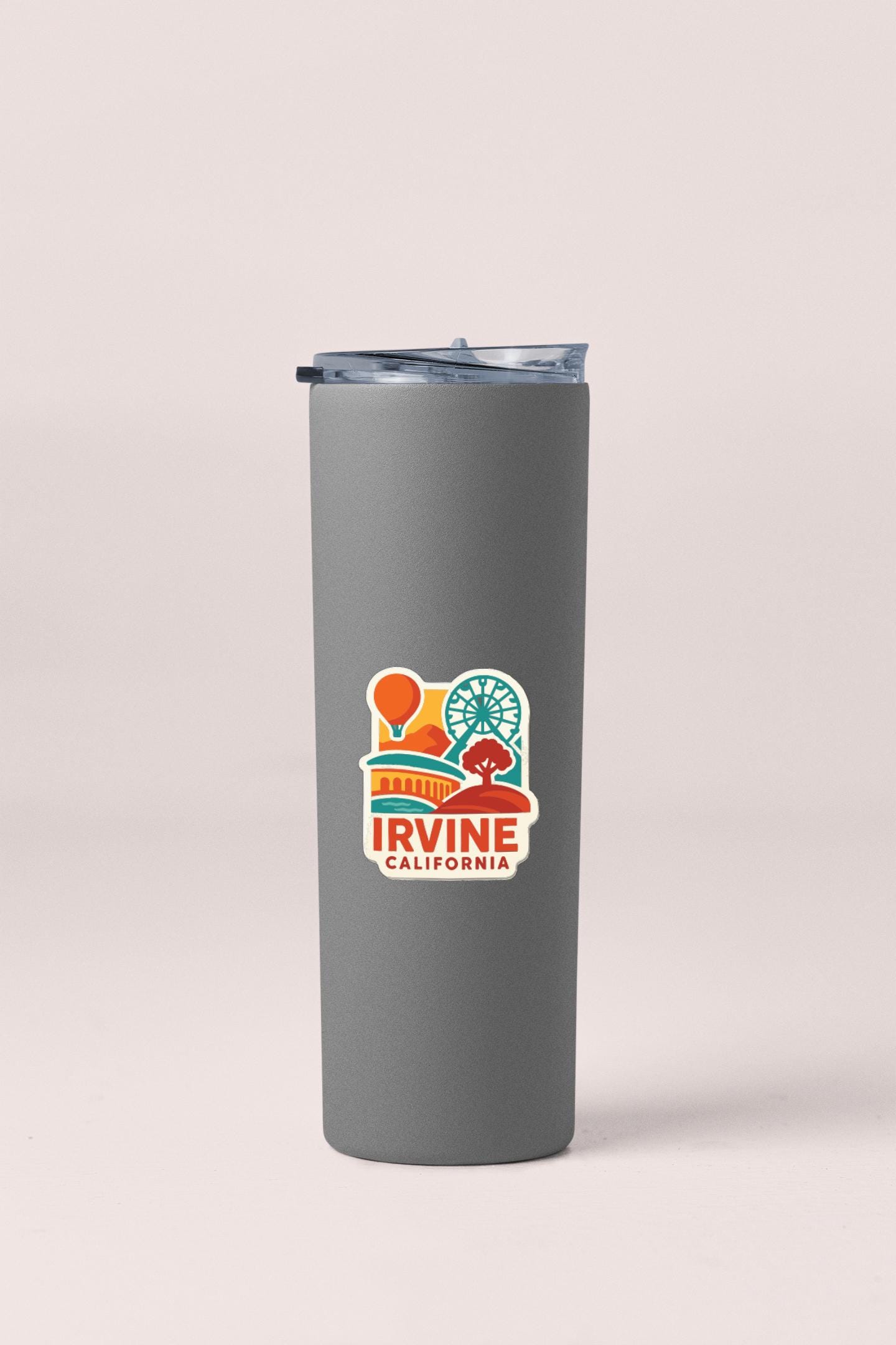 A gray insulated tumbler with a lid and a colorful sticker that says "IRVINE CALIFORNIA".