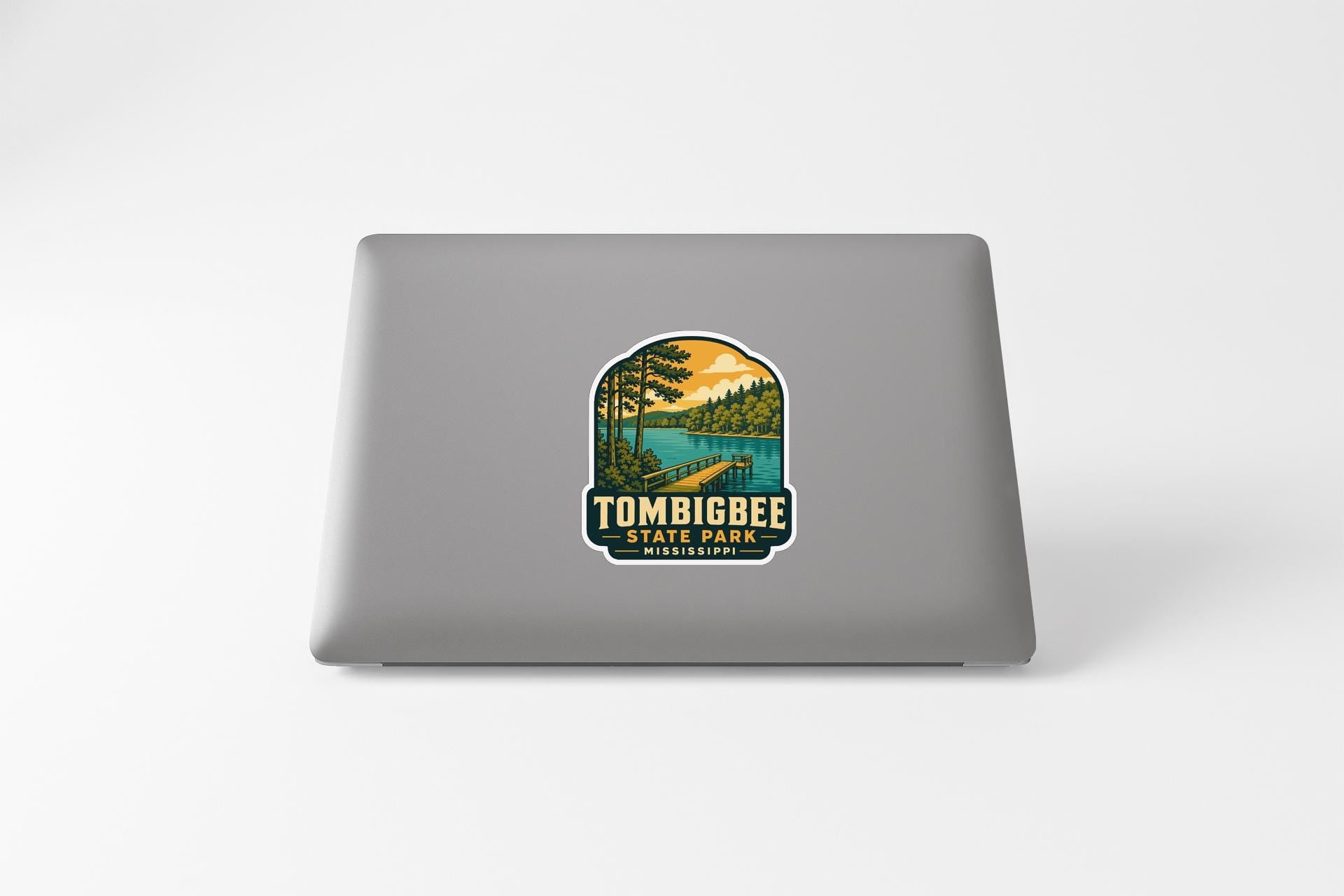a sticker or decal on the back of a laptop, depicting a scenic landscape with a lake, trees, and mountains.