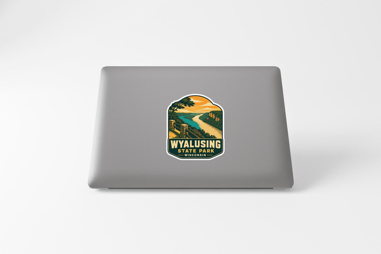 A sticker on the back of a laptop, depicting a scenic landscape with a winding road and a sunset in the background.