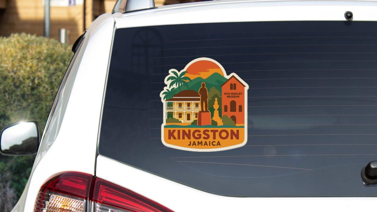 A sticker on the rear window of a car, depicting a tropical scene with a building, palm trees, and mountains, along with the text "KINGSTON JAMAICA".