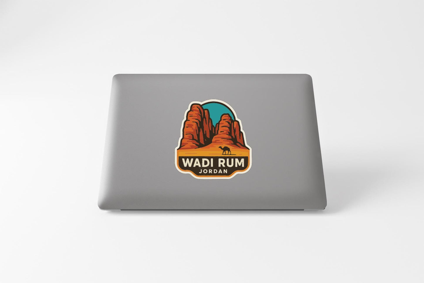 A sticker on the back of a laptop that features a desert landscape with mountains and a camel.