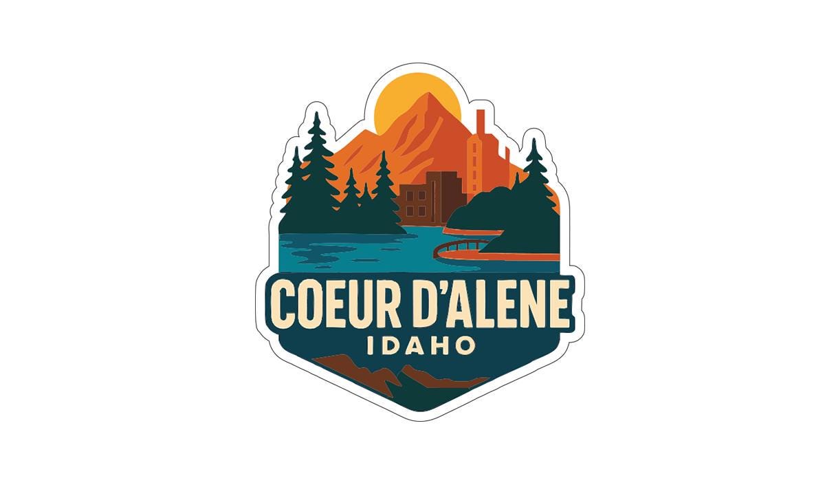 a sticker or logo with a mountain landscape, trees, and a body of water, along with the text "COEUR D'ALENE IDAHO".