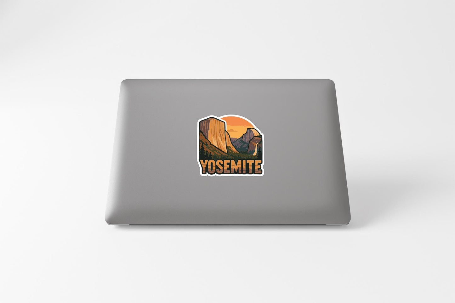A sticker depicting a scenic landscape with mountains and a sunset on a laptop.