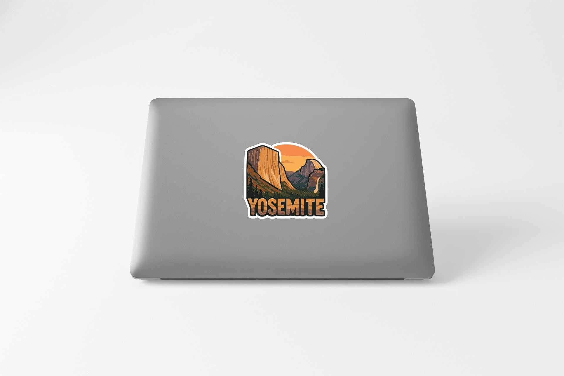 A sticker depicting a scenic landscape with mountains and a sunset on a laptop.