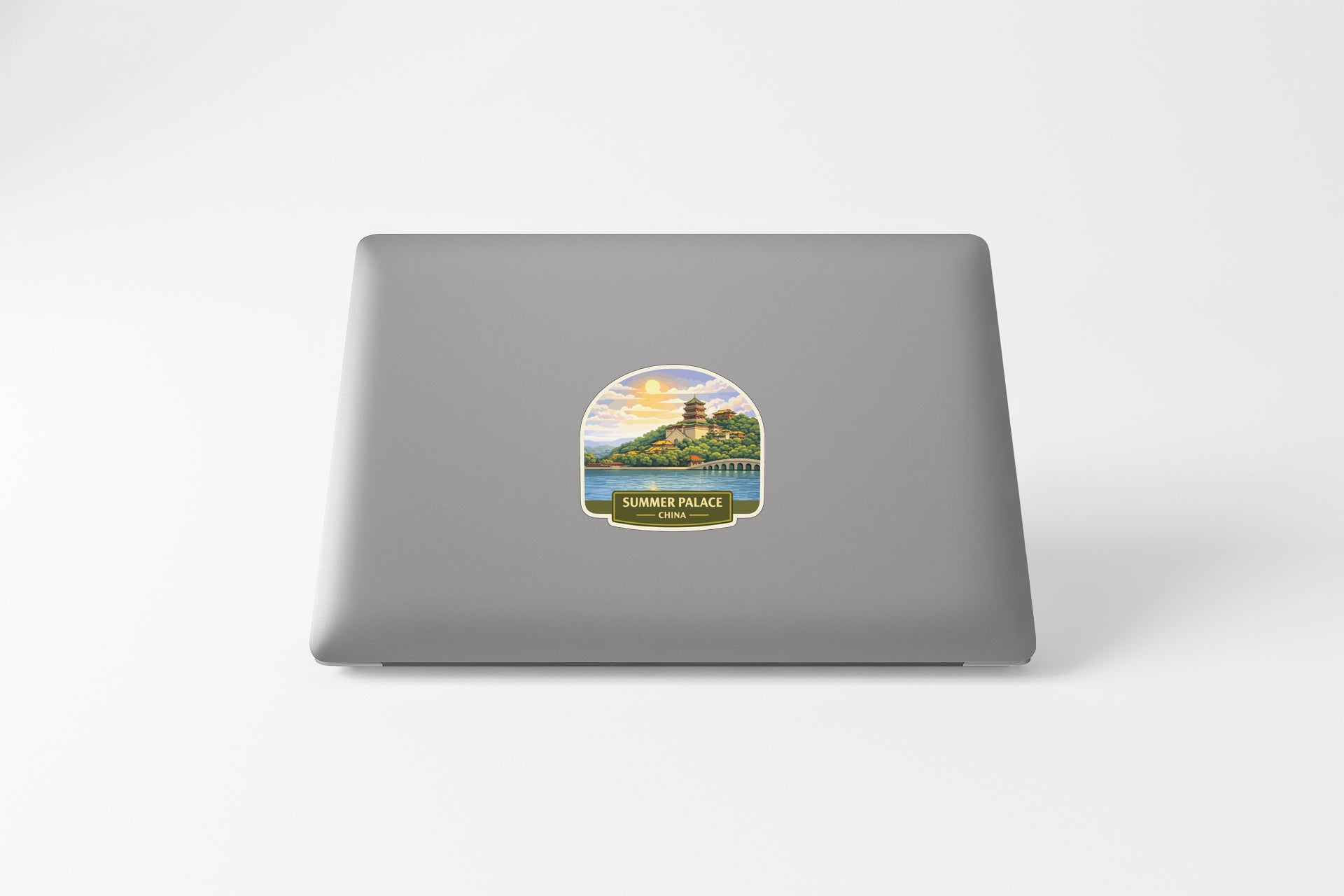 A sticker on the back of a laptop, depicting a scenic landscape with a temple in the distance.