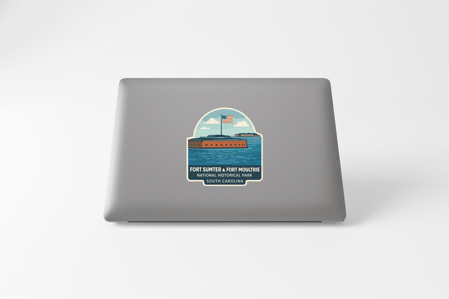 A sticker on the back of a laptop, depicting a ship sailing on a body of water with an American flag flying.