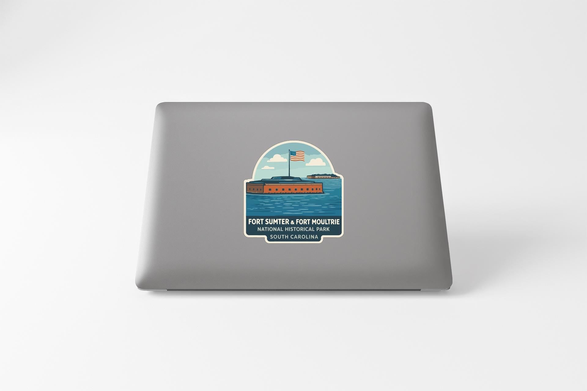 A sticker on the back of a laptop, depicting a ship sailing on a body of water with an American flag flying.
