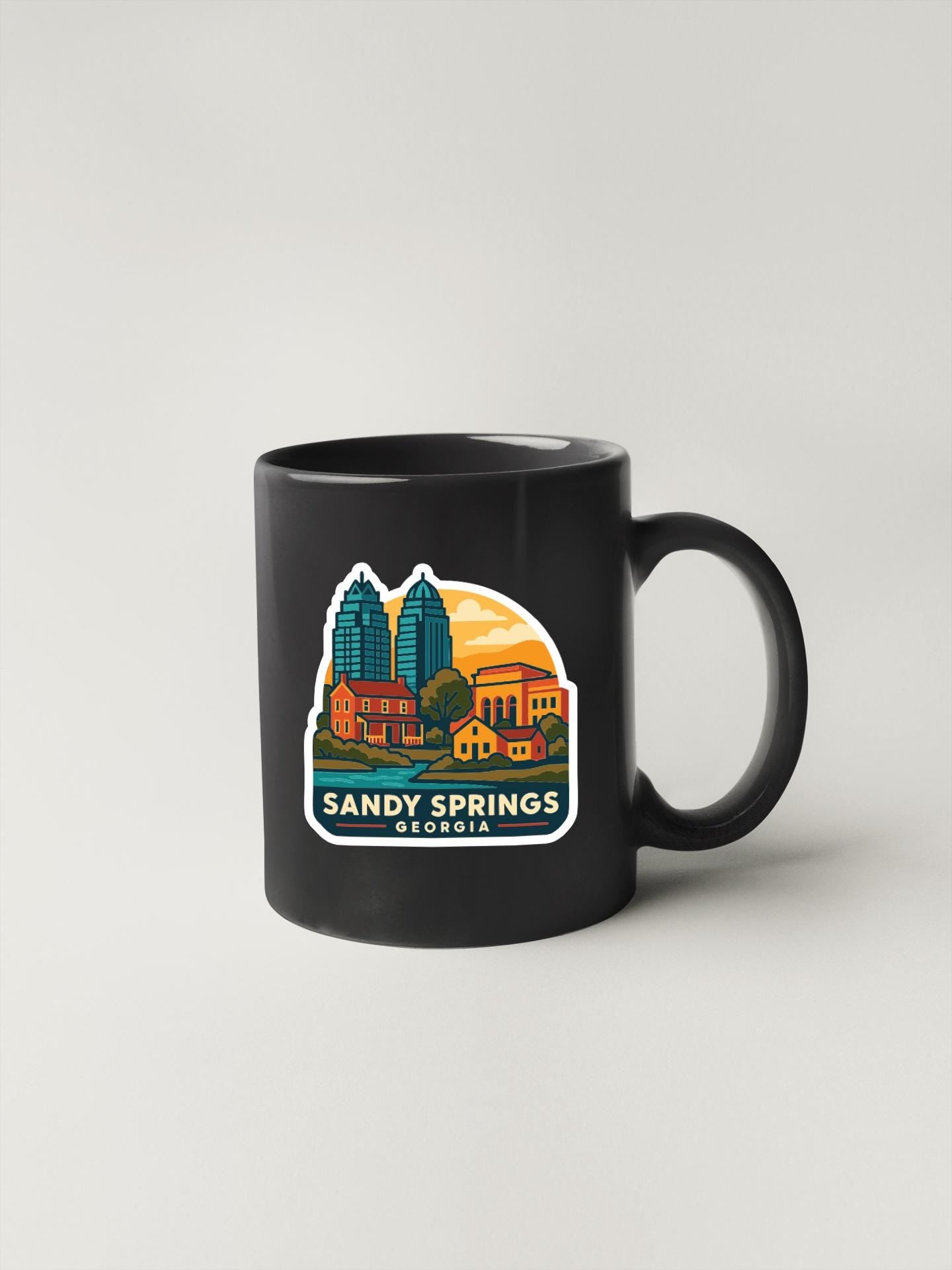 A black coffee mug with a colorful illustration of the city of Sandy Springs, Georgia, featuring buildings, a sunset, and the text "SANDY SPRINGS GEORGIA".