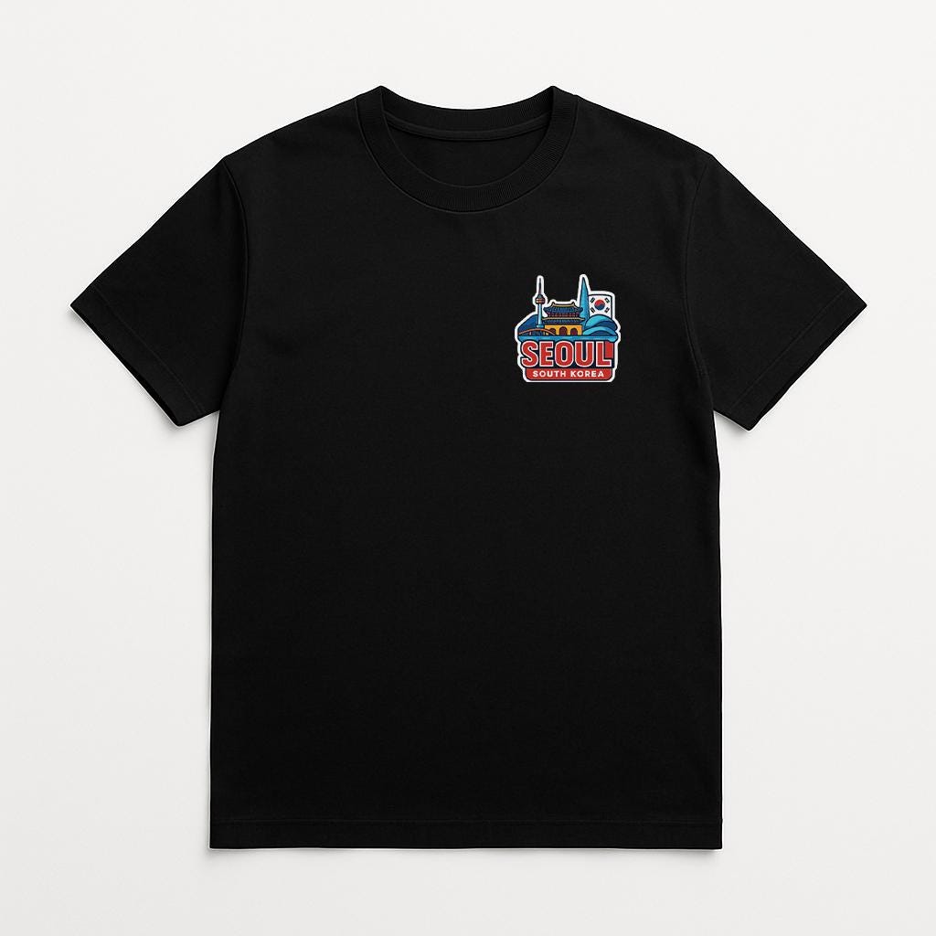 A black t-shirt with a graphic design on the front, depicting a city skyline with the text "SEOUL" prominently displayed.