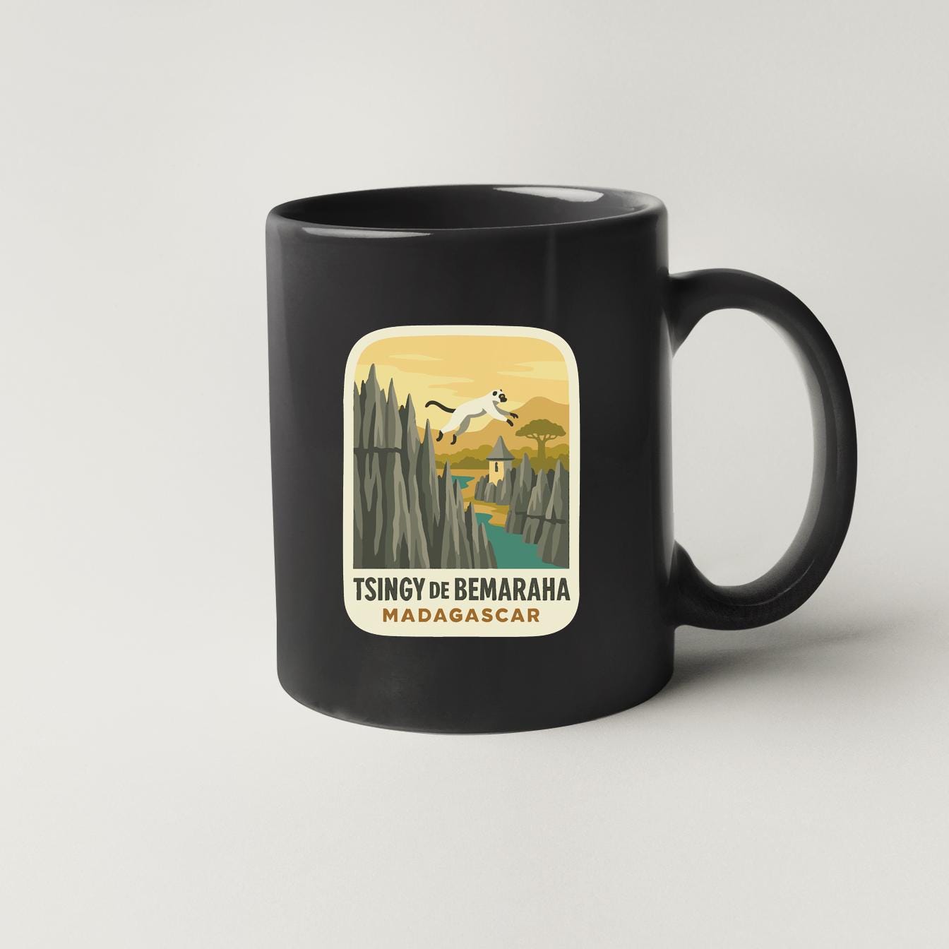 A black coffee mug with a sticker depicting a scenic landscape with mountains, a river, and a bird in flight.