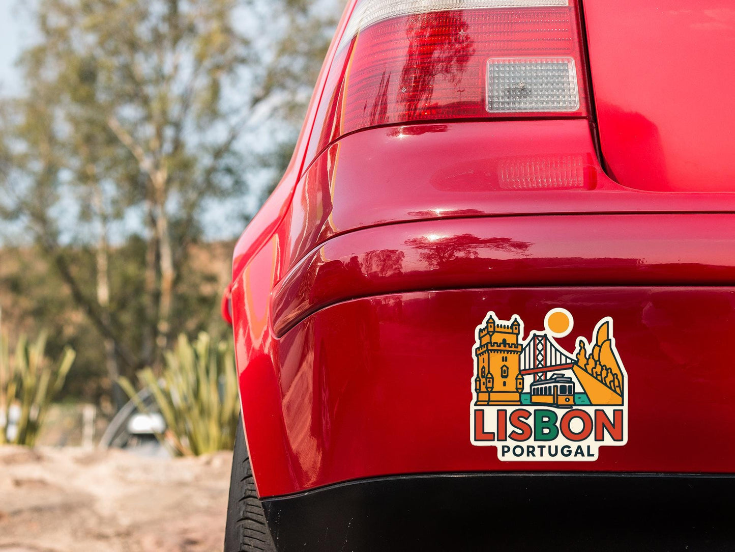 the rear end of a red car with a sticker on the trunk that features a cityscape and the text "LISBON PORTUGAL".