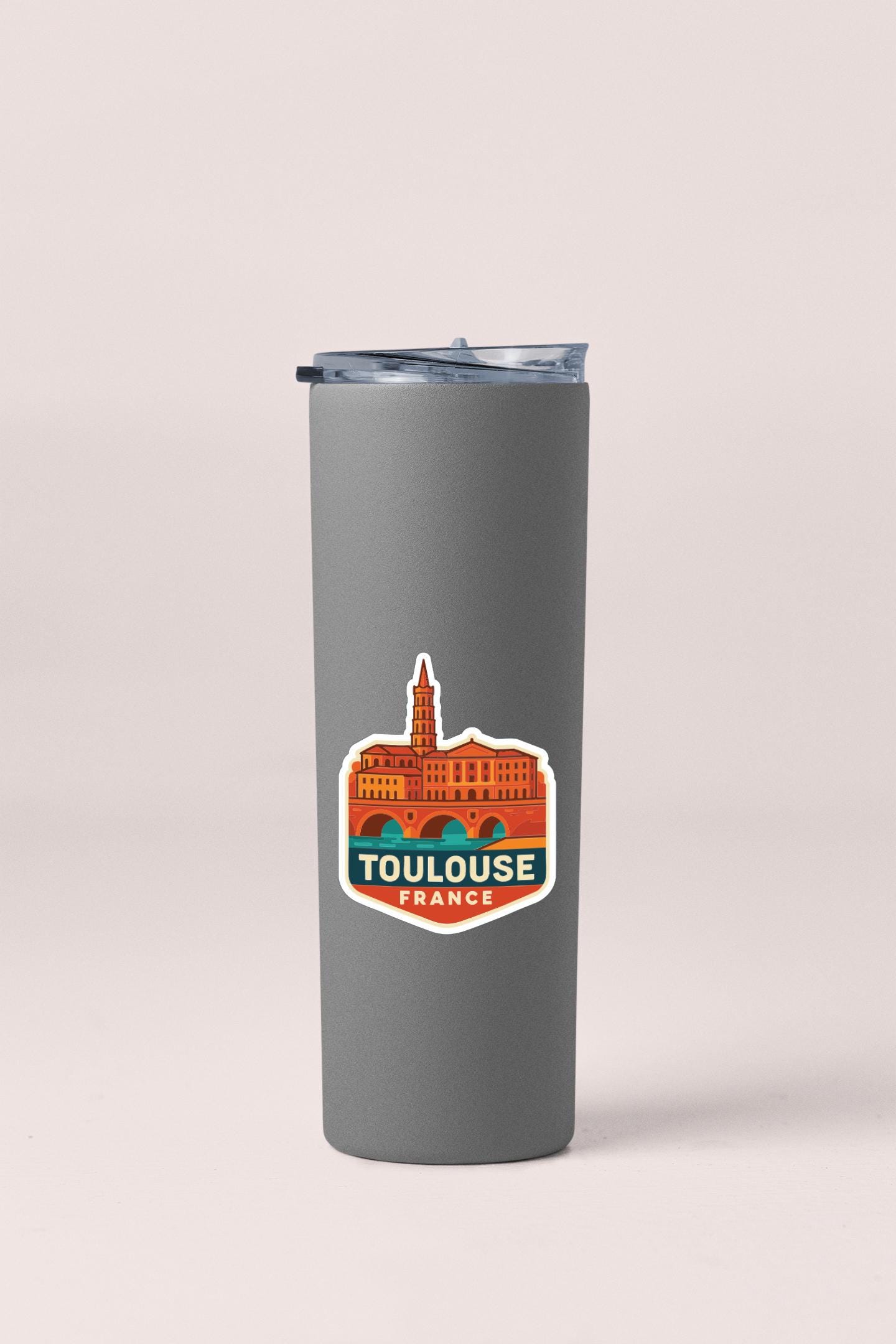 A gray insulated tumbler with a sticker depicting the Toulouse, France, cityscape.