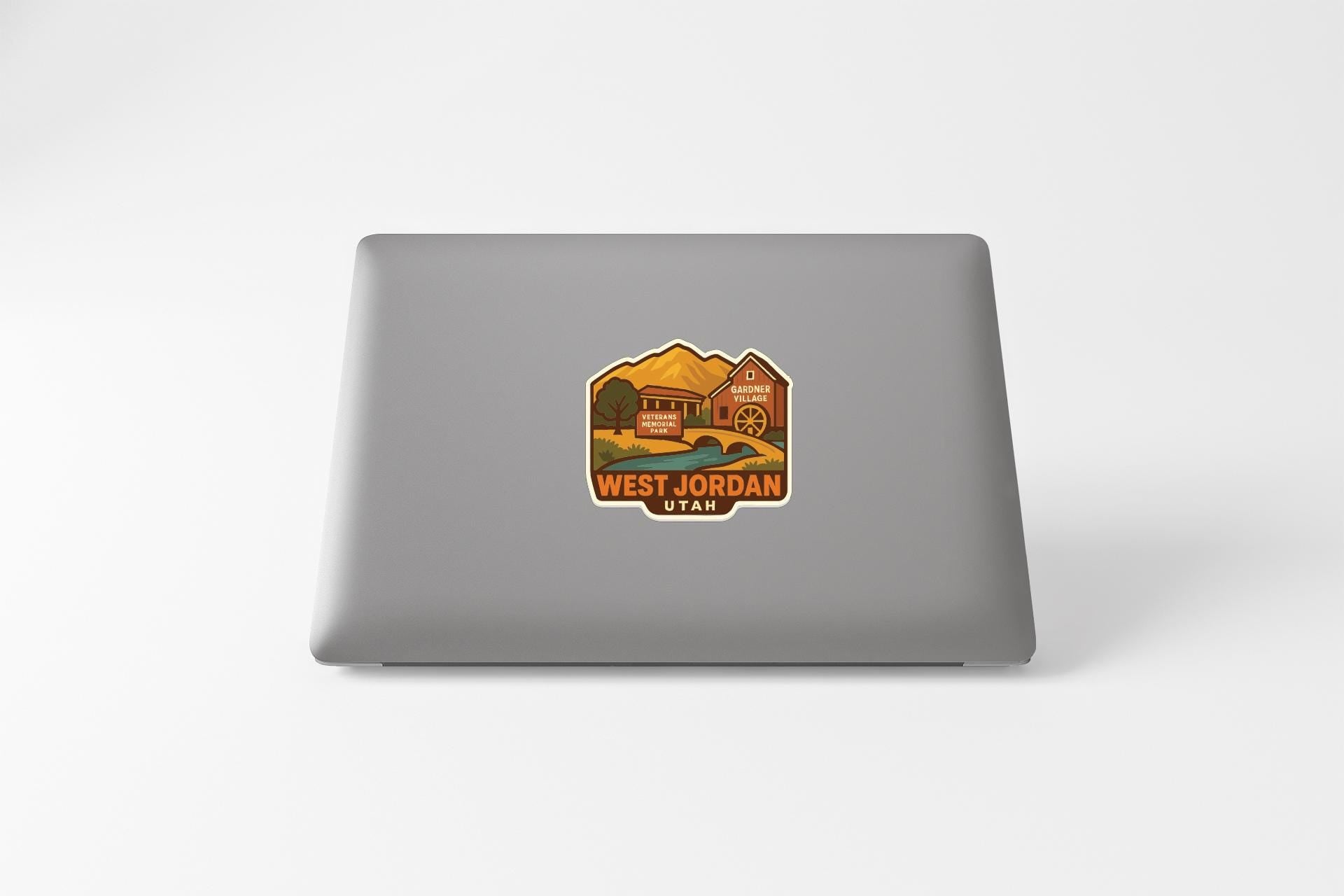 A sticker on the back of a laptop displaying a scenic image of West Jordan, Utah.