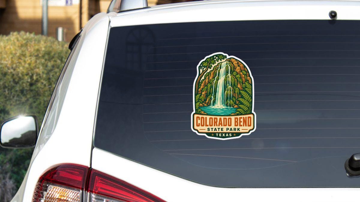 A sticker on the rear window of a white vehicle, depicting a waterfall and the text "COLORADO BEND STATE PARK TEXAS".