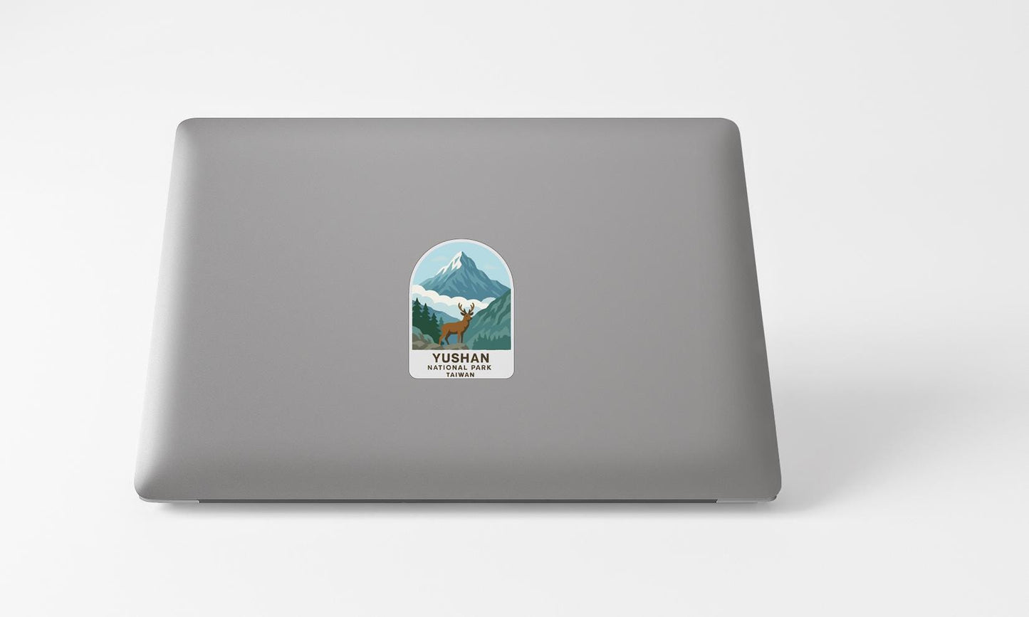 A sticker on the back of a laptop, depicting a mountain landscape with a deer.