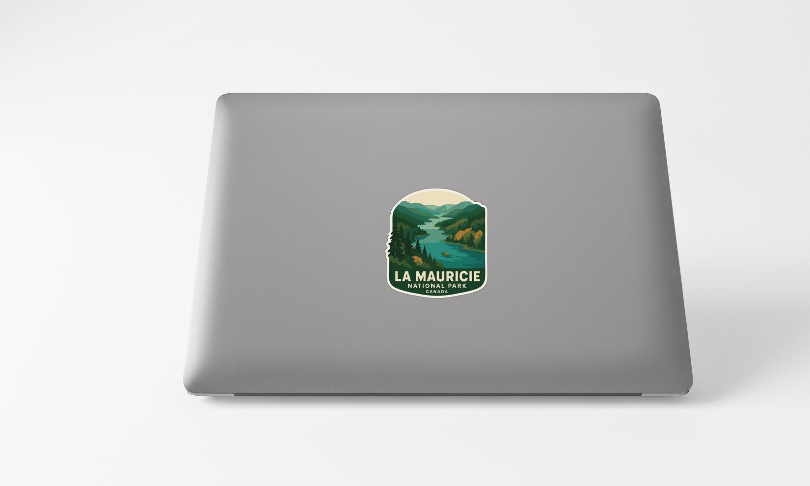 A sticker on the back of a laptop, depicting a scenic landscape with mountains and a river.